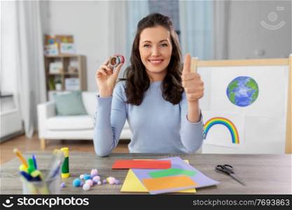 distant education, school and people concept - happy smiling female teacher with color paper and tape having online class of arts and crafts at home and showing thumbs up. teacher having online class of arts and crafts