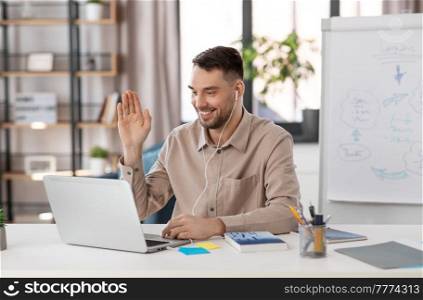 distant education, school and remote job concept - happy smiling male teacher with laptop computer and earphones having online class or video call at home office. teacher with laptop having online class at home
