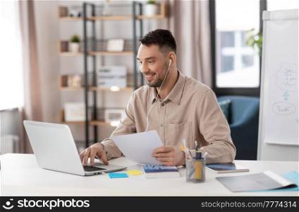 distant education, school and remote job concept - happy smiling male teacher with laptop computer and earphones working at home office. teacher with laptop and earphones working at home