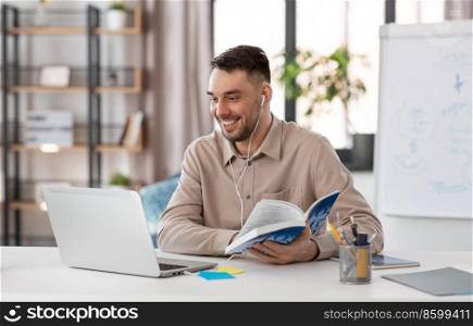 distant education, school and remote job concept - happy smiling male teacher with laptop computer and earphones having online class or video call at home office. teacher with laptop having online class at home