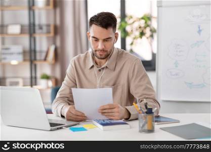 distant education, school and remote job concept - male teacher with laptop computer and earphones working at home office. teacher with laptop and earphones working at home