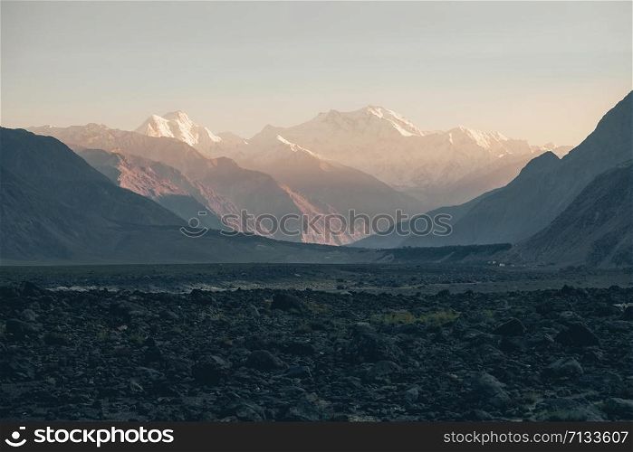 Distant view in the dusk of famous snow capped Nanga Parbat peak or Killer Mountain in the Himalaya range at sunset time. Gilgit Baltistan, Pakistan.