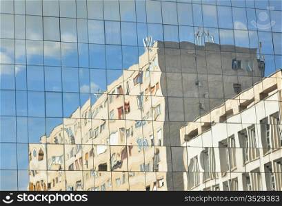 distorted reflexion of an old building on a new building windows
