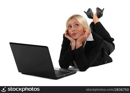 Distracted blond woman laying on floor with laptop