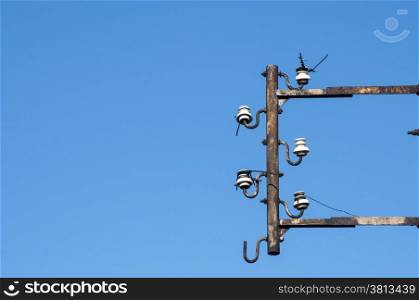 Disused isolators of street electric cables on metal frame on blue sky background