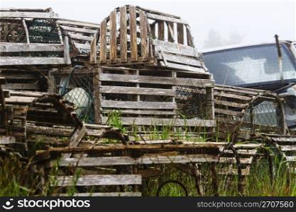 Disused lobster traps piled in growing grass with abandoned truck reflect the growing troubles of the fishing industry