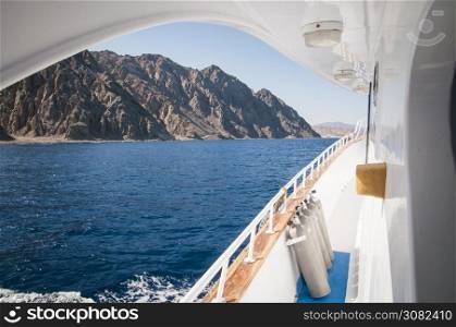 dive boat in the Red sea with dive tanks and mountains on the shoreline