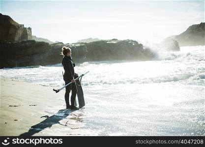 Diver with speargun on beach, Big Sur, California, USA