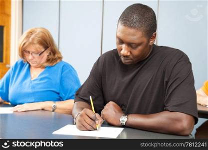Diverse adult education students taking a test in class.