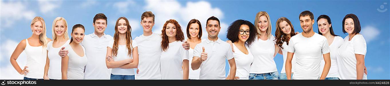 diverse, gesture and people concept - group of happy different body size and age and gender people in white t-shirts hugging showing thumbs up over blue sky and clouds background