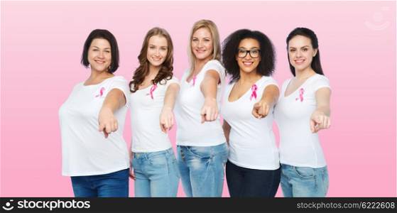 diverse, healthcare and people concept - group of happy different size women in white t-shirts with pink breast cancer awareness ribbon pointing to you over pink background