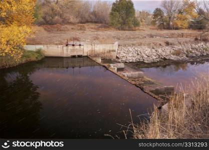 diversion dam with water flowing into irrigation ditch inlet, Cache la Poudre River at Fort Collins, Colorado, fall scenery at dawn