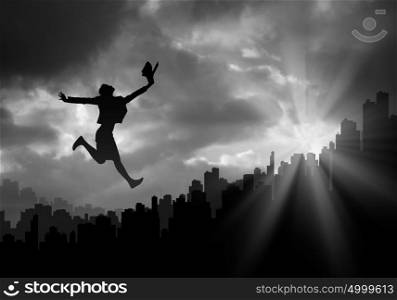 Diversity at work. Silhouette of businesswoman jumping above city against sunset background