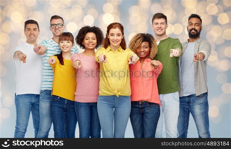 diversity, choice, ethnicity and people concept - international group of happy smiling men and women pointing finger on you over holidays lights background