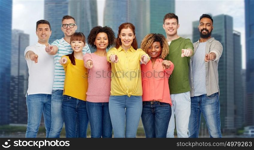 diversity, choice, ethnicity and people concept - international group of happy smiling men and women pointing finger on you over singapore city skyscrapers background. international group of people pointing on you