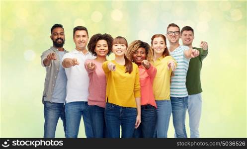 diversity, choice, ethnicity and people concept - international group of happy smiling men and women pointing finger on you over summer green lights background. international group of people pointing on you