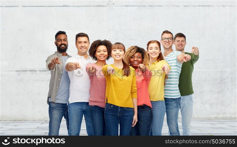 diversity, choice, ethnicity and people concept - international group of happy smiling men and women pointing finger on you over stone wall background. international group of people pointing on you