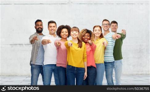 diversity, choice, ethnicity and people concept - international group of happy smiling men and women pointing finger on you over stone wall background. international group of people pointing on you