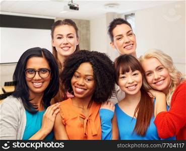 diversity, education and people concept - group of happy smiling student women hugging over university background. group of happy student women hugging at university