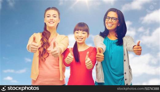 diversity, ethnicity and people concept - international group of happy smiling different women showing thumbs up over blue sky and clouds background. international happy women showing thumbs up