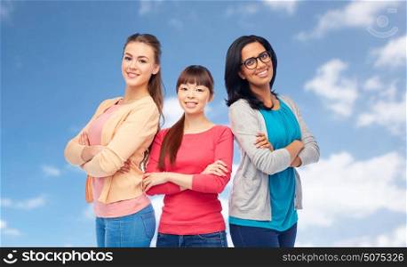 diversity, ethnicity and people concept - international group of happy smiling different women over blue sky and clouds background. international group of happy smiling women