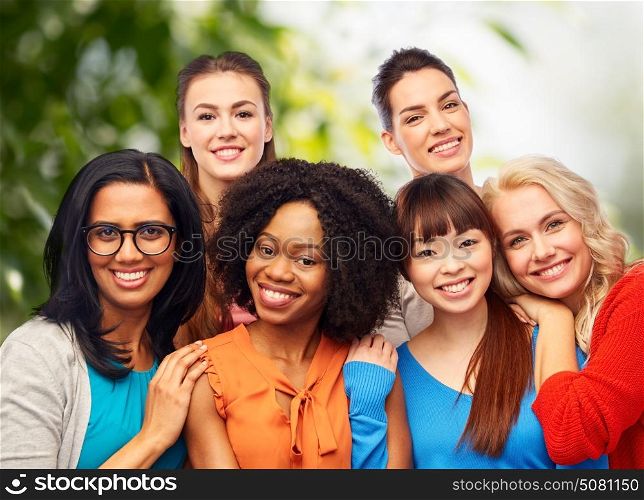 diversity, ethnicity and people concept - international group of happy smiling different women hugging over green natural background. international group of happy women hugging