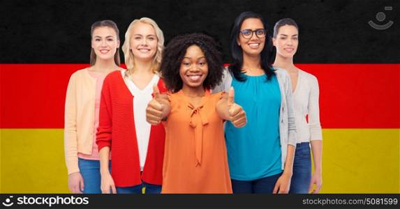 diversity, ethnicity and people concept - international group of happy smiling different women showing thumbs up over german flag background. international german women showing thumbs up