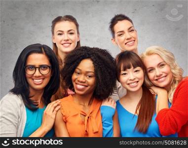 diversity, ethnicity and people concept - international group of happy smiling different women hugging over gray concrete wall background. international group of happy women hugging