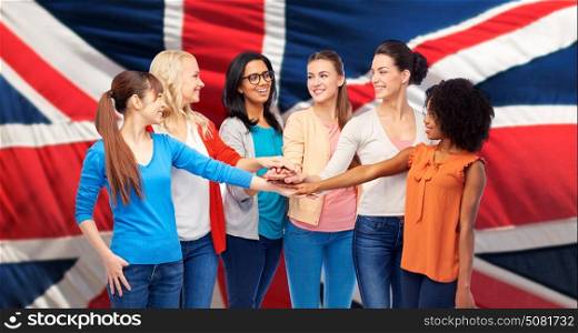 diversity, ethnicity and people concept - international group of happy smiling different women holding hands together over british flag background. united nternational women over british flag