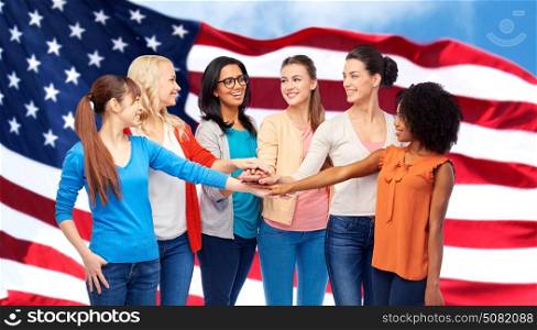 diversity, ethnicity and people concept - international group of happy smiling different women holding hands together over american flag background. united international women over american flag