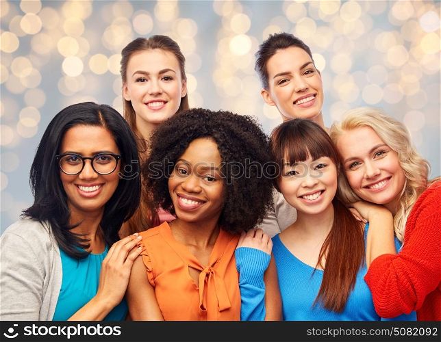 diversity, ethnicity and people concept - international group of happy smiling different women hugging over holidays lights background. international group of happy women hugging