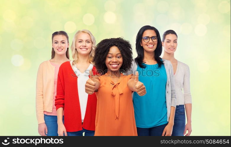 diversity, ethnicity and people concept - international group of happy smiling different women showing thumbs up over summer green lights background. international group of women showing thumbs up. international group of women showing thumbs up