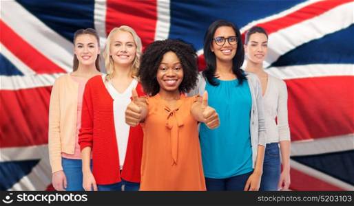 diversity, ethnicity and people concept - international group of happy smiling different women showing thumbs up over english flag background. international english women showing thumbs up