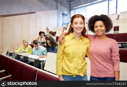 diversity, friendship and education concept - happy smiling student women hugging over university background. happy smiling student women hugging at university