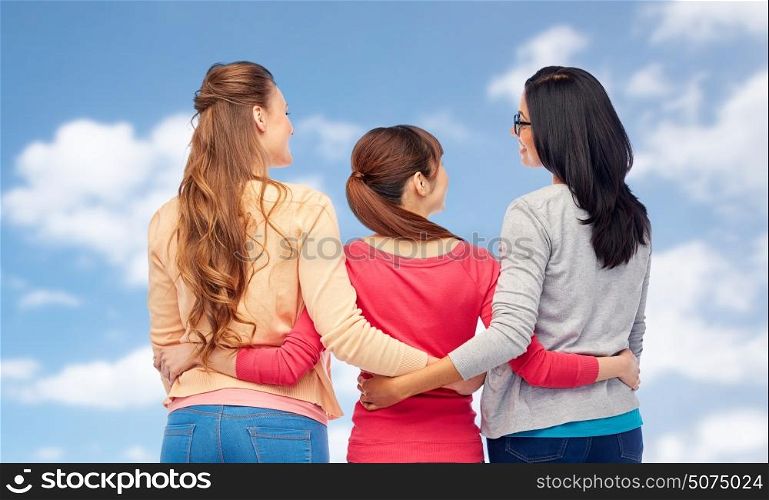 diversity, friendship and people concept - international group of happy different women hugging from back over blue sky and clouds background. international happy women from back hugging