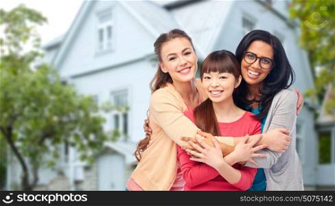 diversity, friendship and people concept - international group of happy smiling different women hugging over house background. international group of happy women hugging