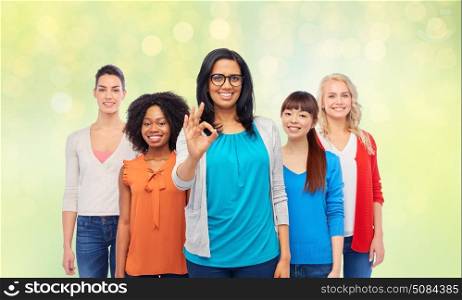 diversity, gesture and people concept - international group of happy smiling different women showing ok hand sign over summer green lights background. international group of happy women showing ok. international group of happy women showing ok