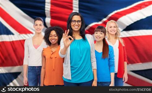 diversity, gesture and people concept - international group of happy smiling different women showing ok hand sign over english flag background. international english happy women showing ok