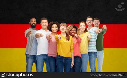 diversity, immigration and people concept - international group of happy smiling men and women pointing finger on you over german flag background. international group of people pointing on you
