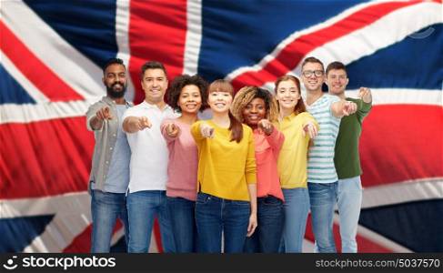 diversity, immigration and people concept - international group of happy smiling men and women pointing finger on you over british flag background. international group of people pointing on you