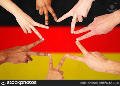 diversity, immigration, ethnicity, international and people concept - group of hands showing peace hand sign over german flag background. group of international people showing peace sign