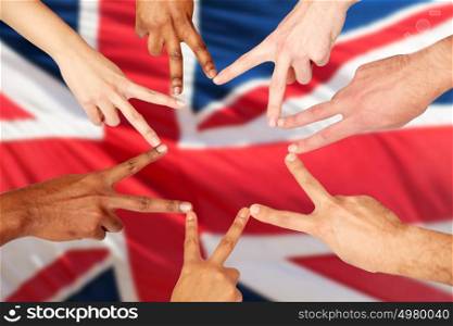 diversity, immigration, ethnicity, international and people concept - group of hands showing peace hand sign over british flag background. group of international people showing peace sign