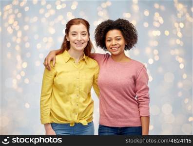 diversity, international, ethnicity, friendship and people concept - happy smiling women hugging over holidays lights background