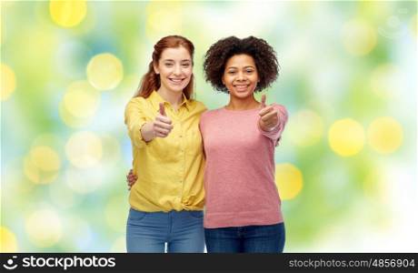 diversity, international, ethnicity, friendship and people concept - happy smiling women showing thumbs up and hugging over green holidays lights background