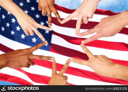diversity, patriotism, ethnicity, international and people concept - group of hands showing peace hand sign over american flag background. group of international people showing peace sign