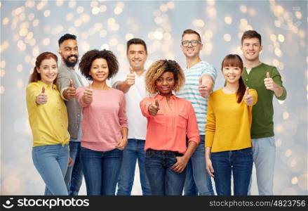 diversity, race, ethnicity and people concept - international group of happy smiling men and women showing thumbs up over holidays lights background
