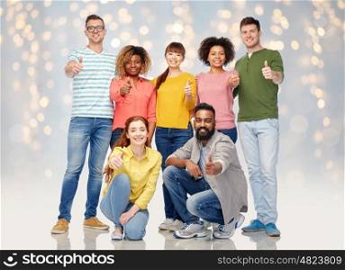 diversity, race, ethnicity and people concept - international group of happy smiling men and women showing thumbs up over holidays lights background