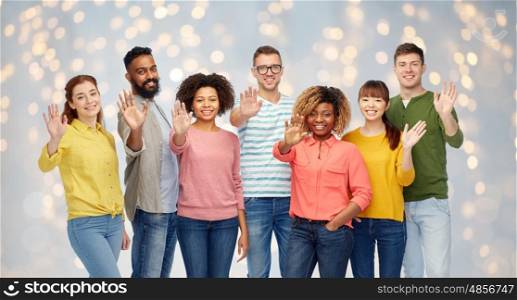 diversity, race, ethnicity and people concept - international group of happy smiling men and women waving hand over holidays lights background