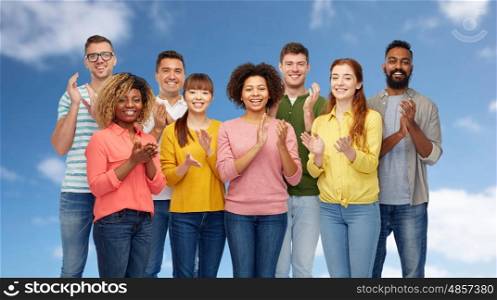 diversity, race, ethnicity and people concept - international group of happy smiling men and women over blue sky and clouds background
