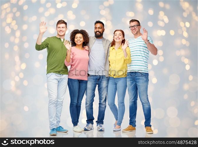 diversity, race, ethnicity and people concept - international group of happy smiling men and women waving hands over holidays lights background
